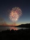 Fireworks blaze over a coastline as a crowd gathers to watch