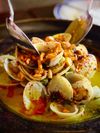 Close up of the dish "Sexy Clams"—clams with garlic and coconut milk, topped with chili cashews—in restaurant Fondo Lo Que Hay in Panama City