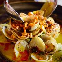Close up of the dish "Sexy Clams"—clams with garlic and coconut milk, topped with chili cashews—in restaurant Fondo Lo Que Hay in Panama City