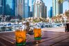 Two glasses of tea at outdoor cafe on marina with boats and high rise buildings in the background.