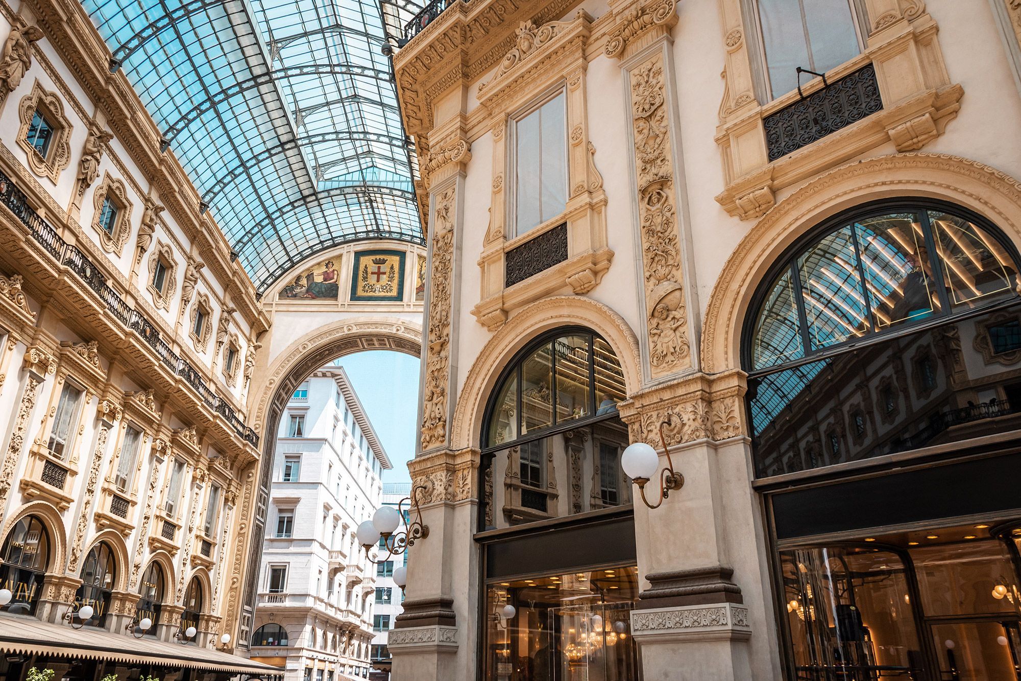 Interior view of the Galleria Vittorio Emanuele II with ornate details on the walls and windows on the ceiling.