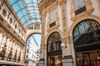 Interior view of the Galleria Vittorio Emanuele II with ornate details on the walls and windows on the ceiling.
