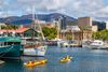 Kayakers paddling past yachts in a harbor.