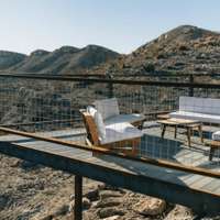 Sun covers the raised terrace and white-cushioned outdoor furniture at a Vrbo holiday rental out in the desert in Terlingua, Texas
