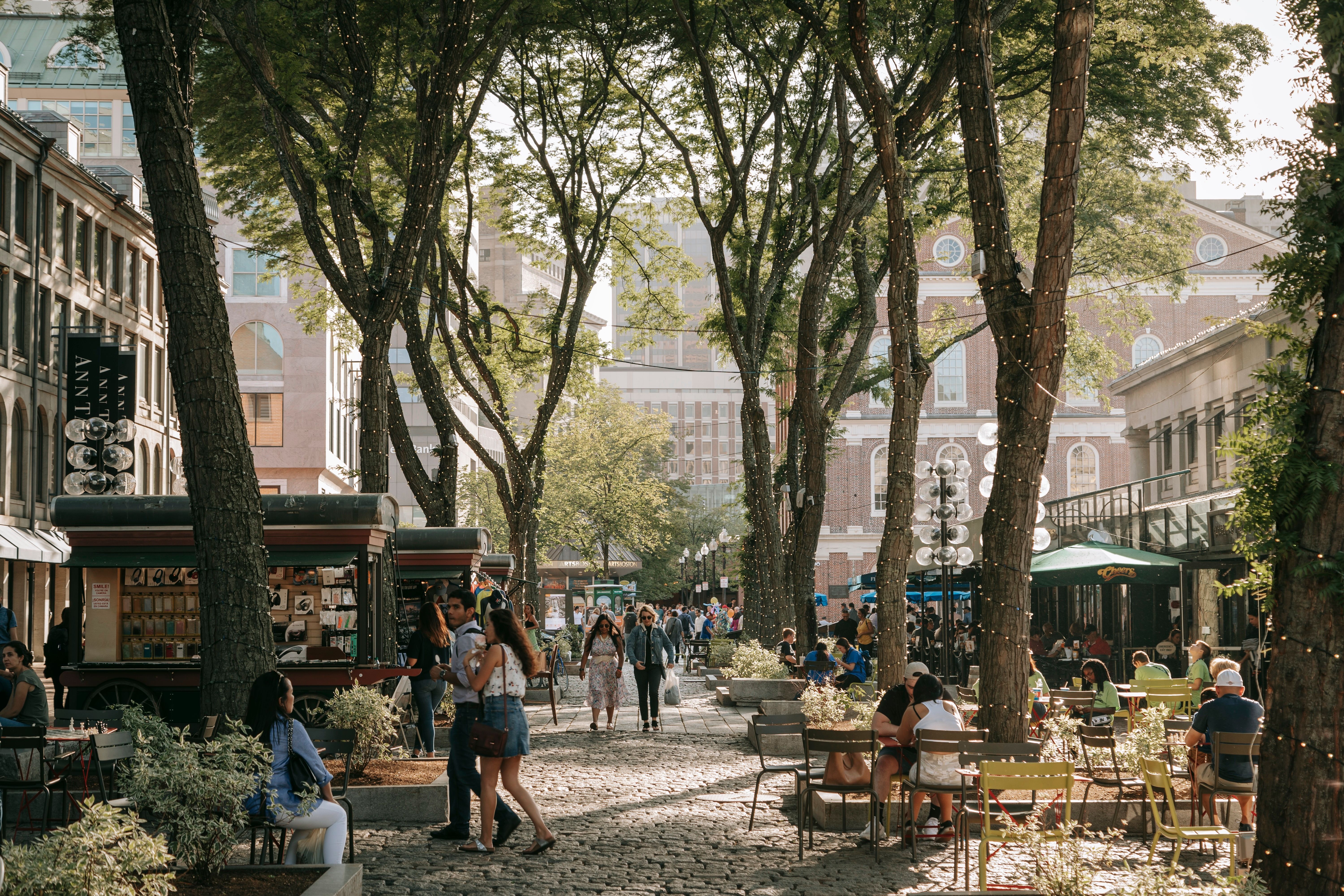 People walk around the tree-lined, cobbled streets of Quincy Market in Boston, Massachusetts