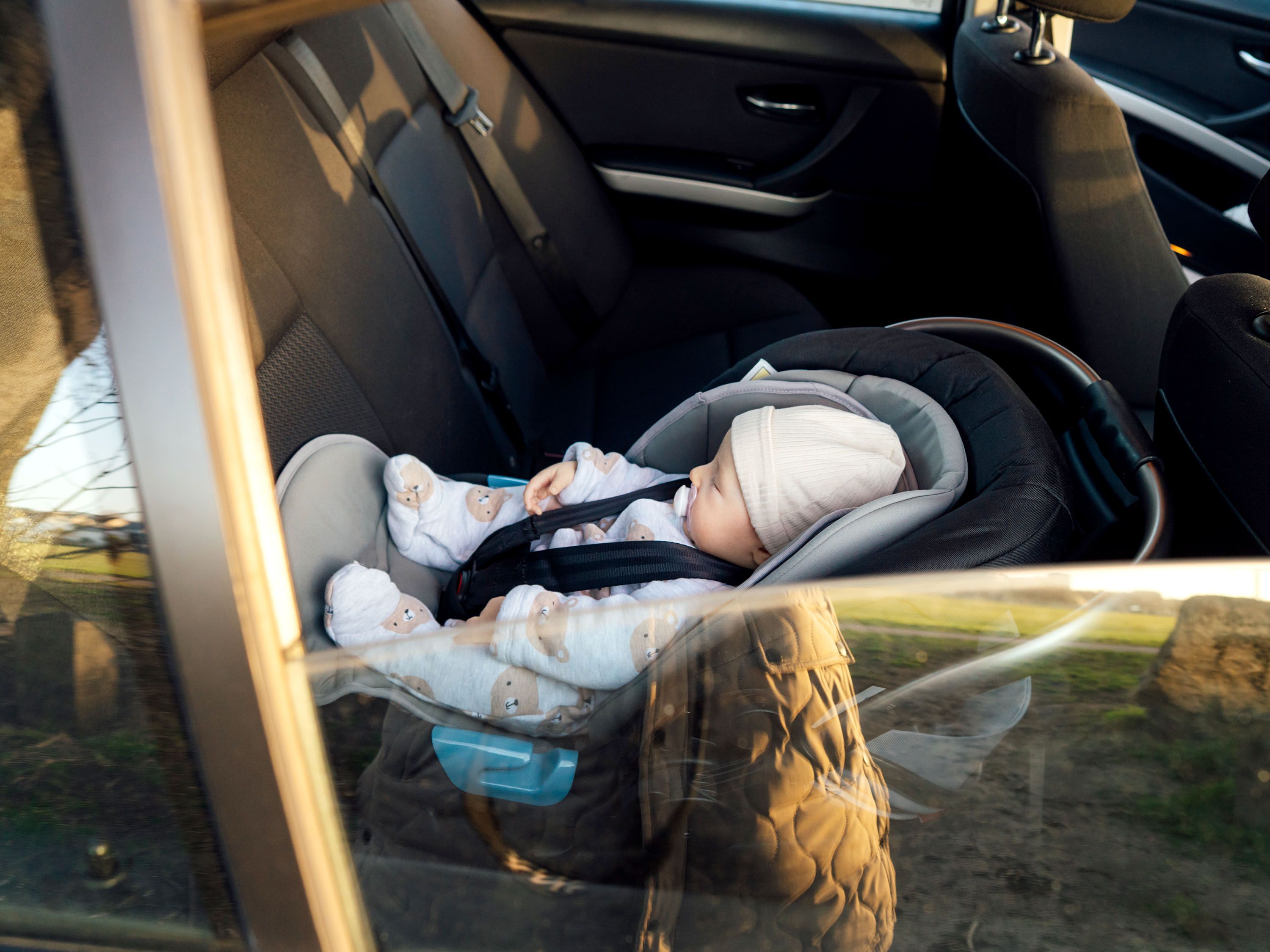 Window reflection and baby in car seat riding in a car.