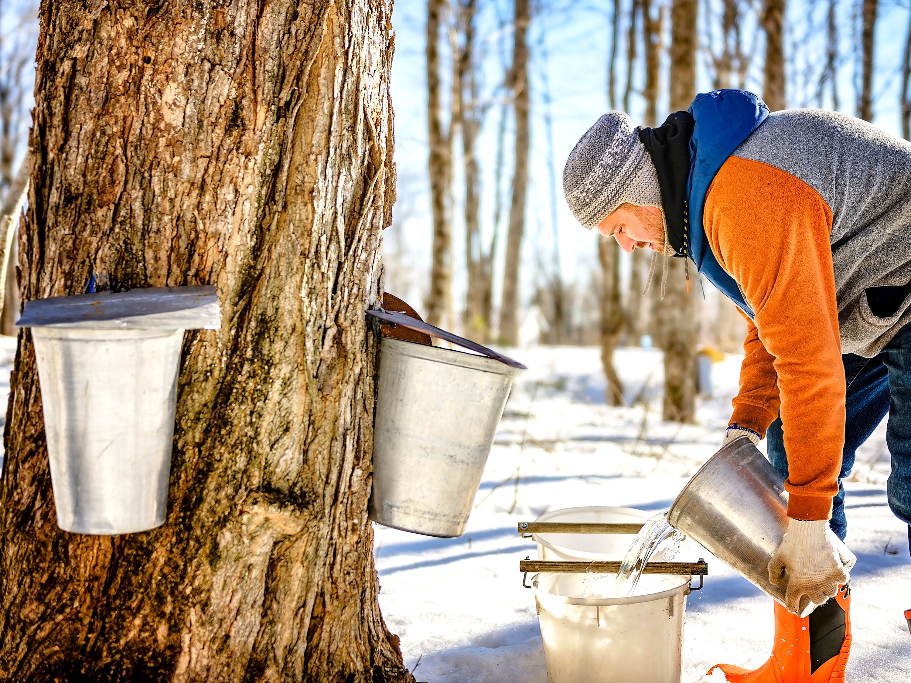 A man pours clear liquid from one bucket into another.