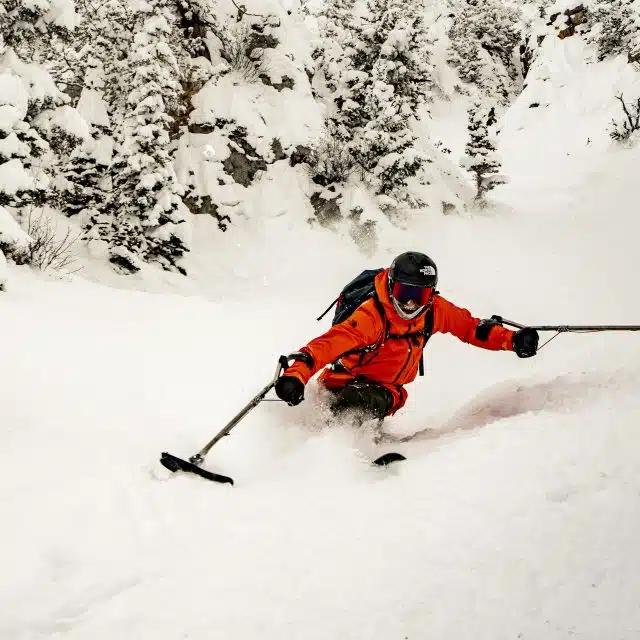 Pro skier and accessibility activist Vasu Sojitra skis down a mountain in ski gear