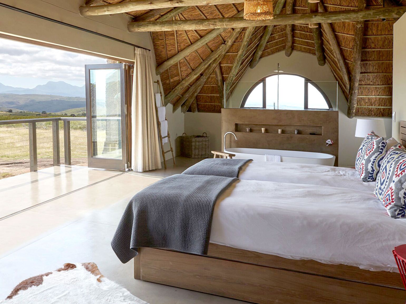 Double bed in room accomodations with open air wall overlooking game reserve.