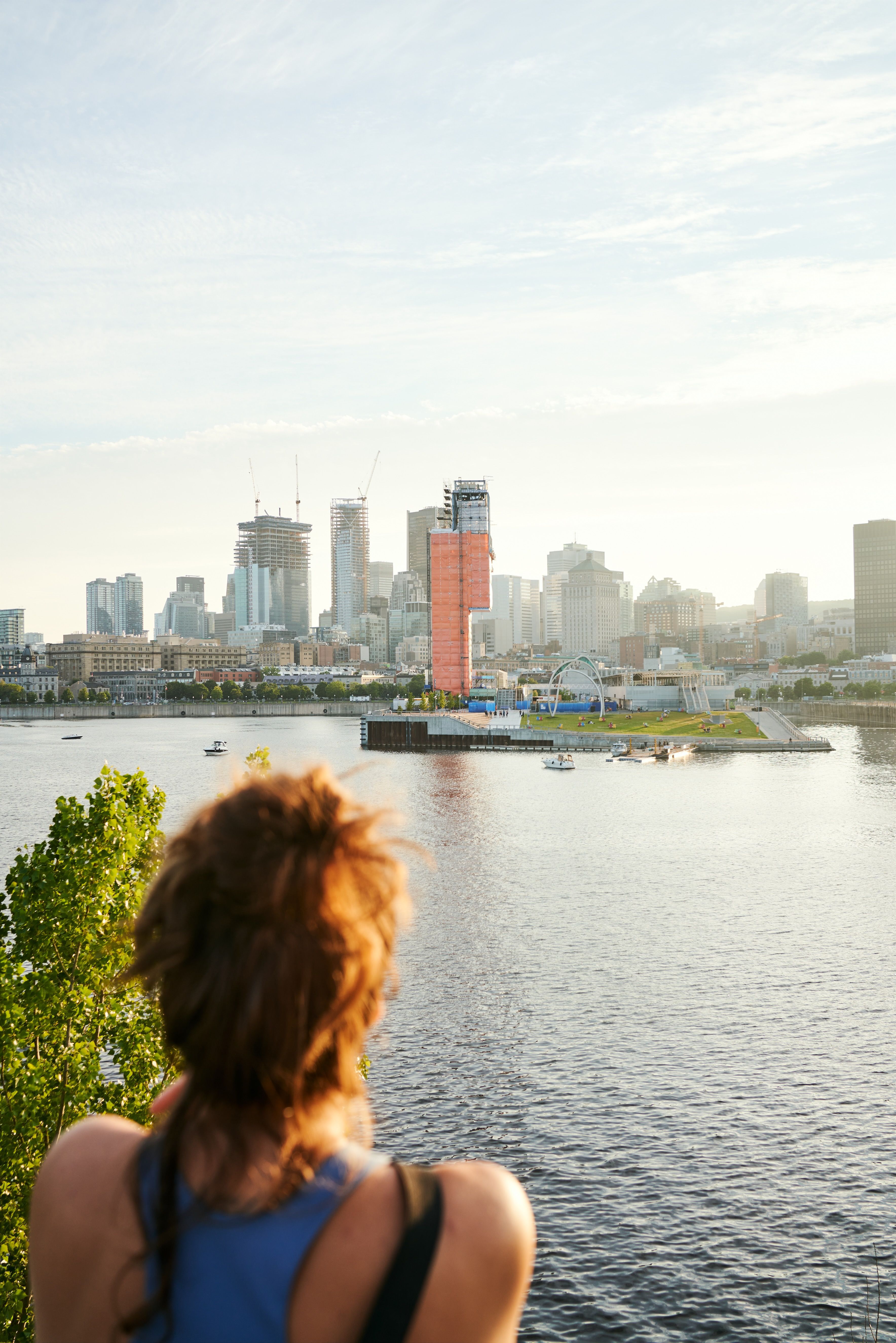 A woman with red hair looks out over the Saint Lawrence River to the city skyline in Montreal, Québec