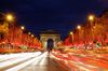 A street lined with Christmas lit trees and a large arch over the road and blurred lights of moving cars.