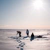 Three people ice fishing in the snow in Yellowknife, Canada