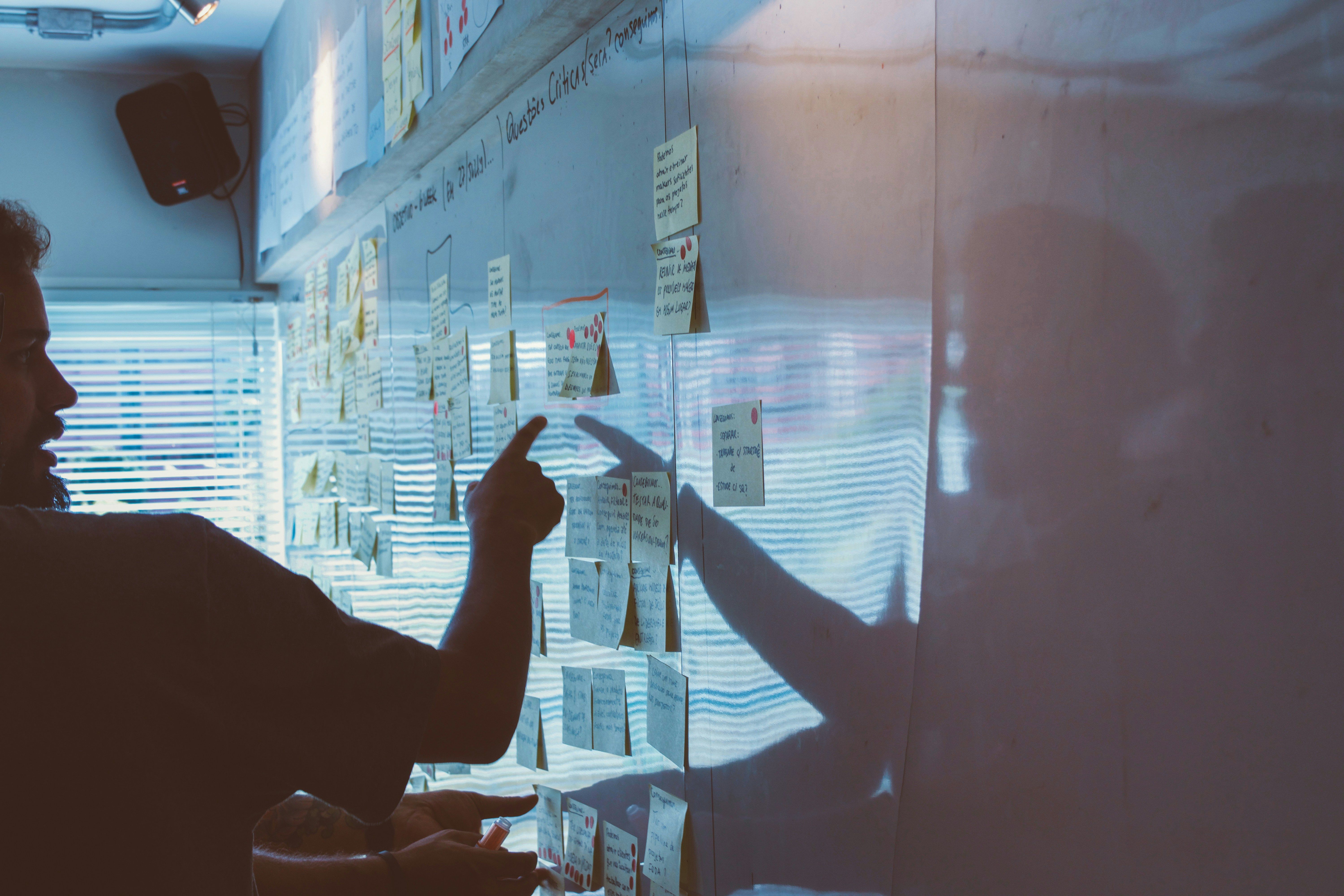 Person pointing white board of post it notes strategy session