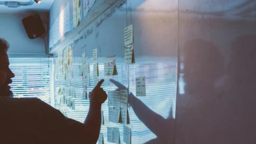Person pointing white board of post it notes strategy session