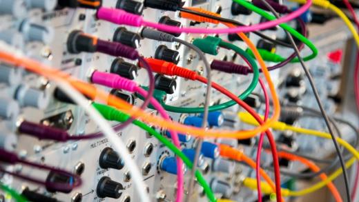 Modular synthesizer with numerous colorful patch cables.