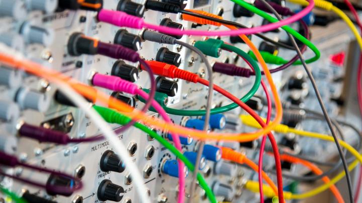 Modular synthesizer with numerous colorful patch cables.