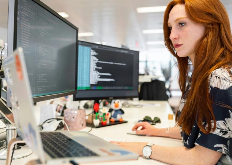 Women engineer on computer two monitors red hair