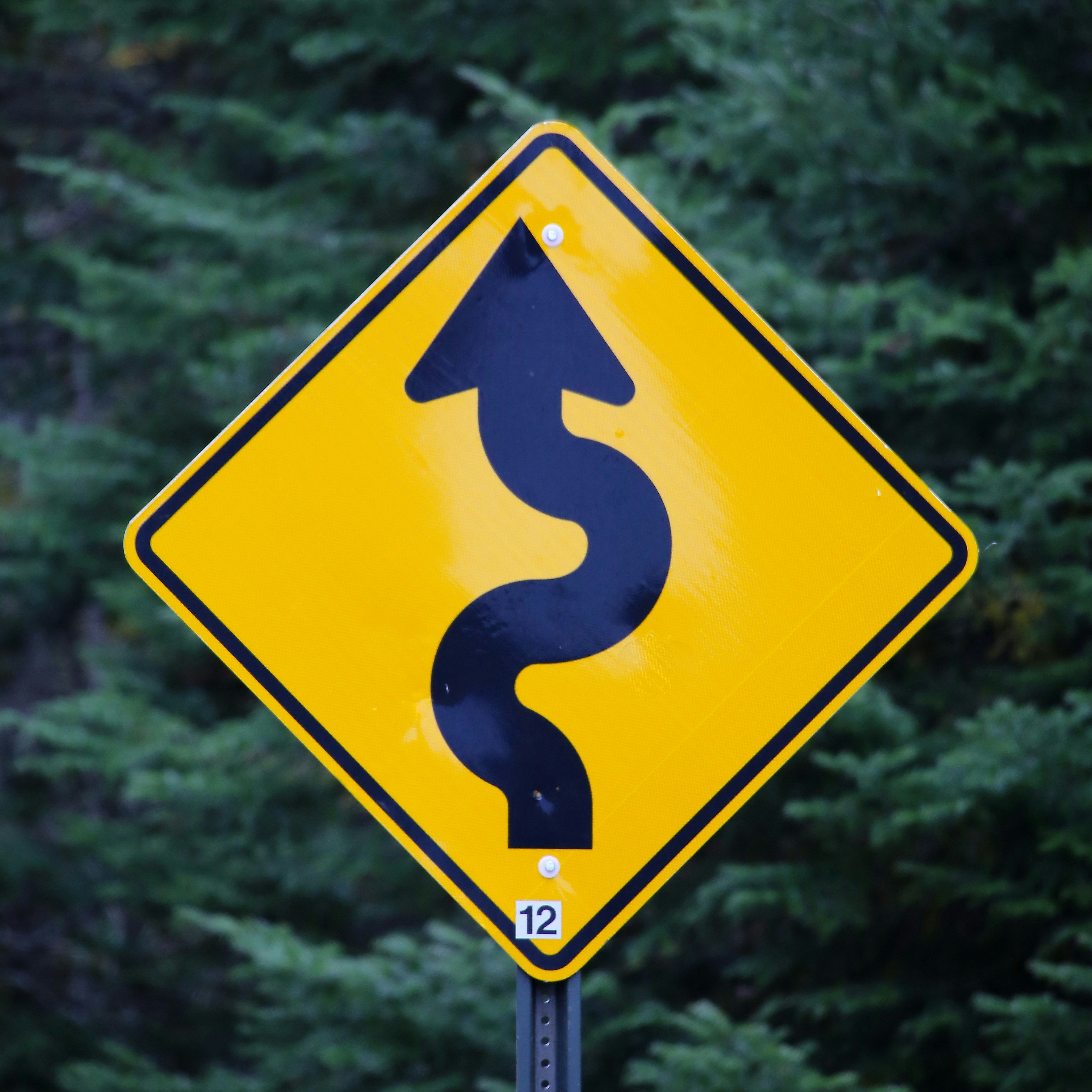 Yellow diamond-shaped road sign with a black wavy arrow pointing up, and the number 12.