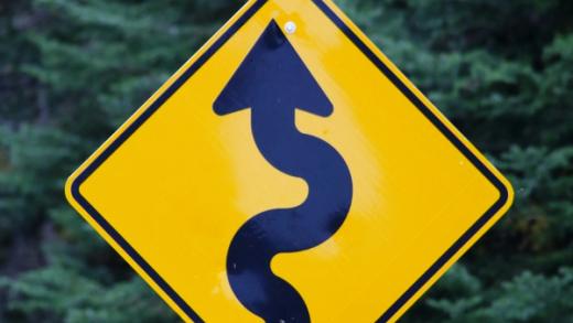 Yellow diamond-shaped road sign with a black wavy arrow pointing up, and the number 12.