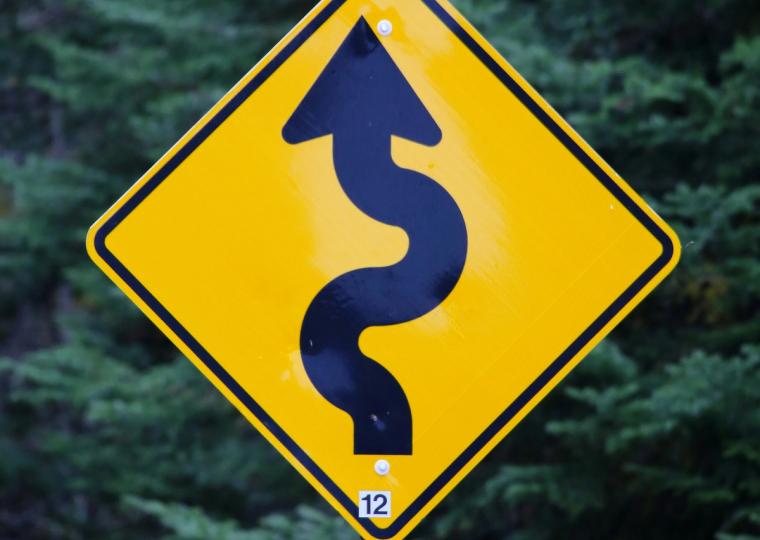 Yellow diamond-shaped road sign with a black wavy arrow pointing up, and the number 12.