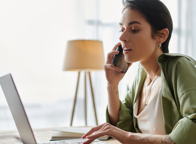 Woman on her phone reviewing her computer