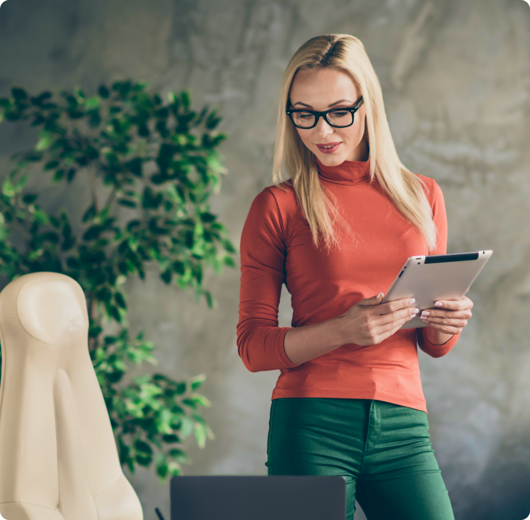 A woman with long blonde hair and glasses stands holding a tablet. She wears an orange turtleneck, exuding a relaxed, professional vibe.