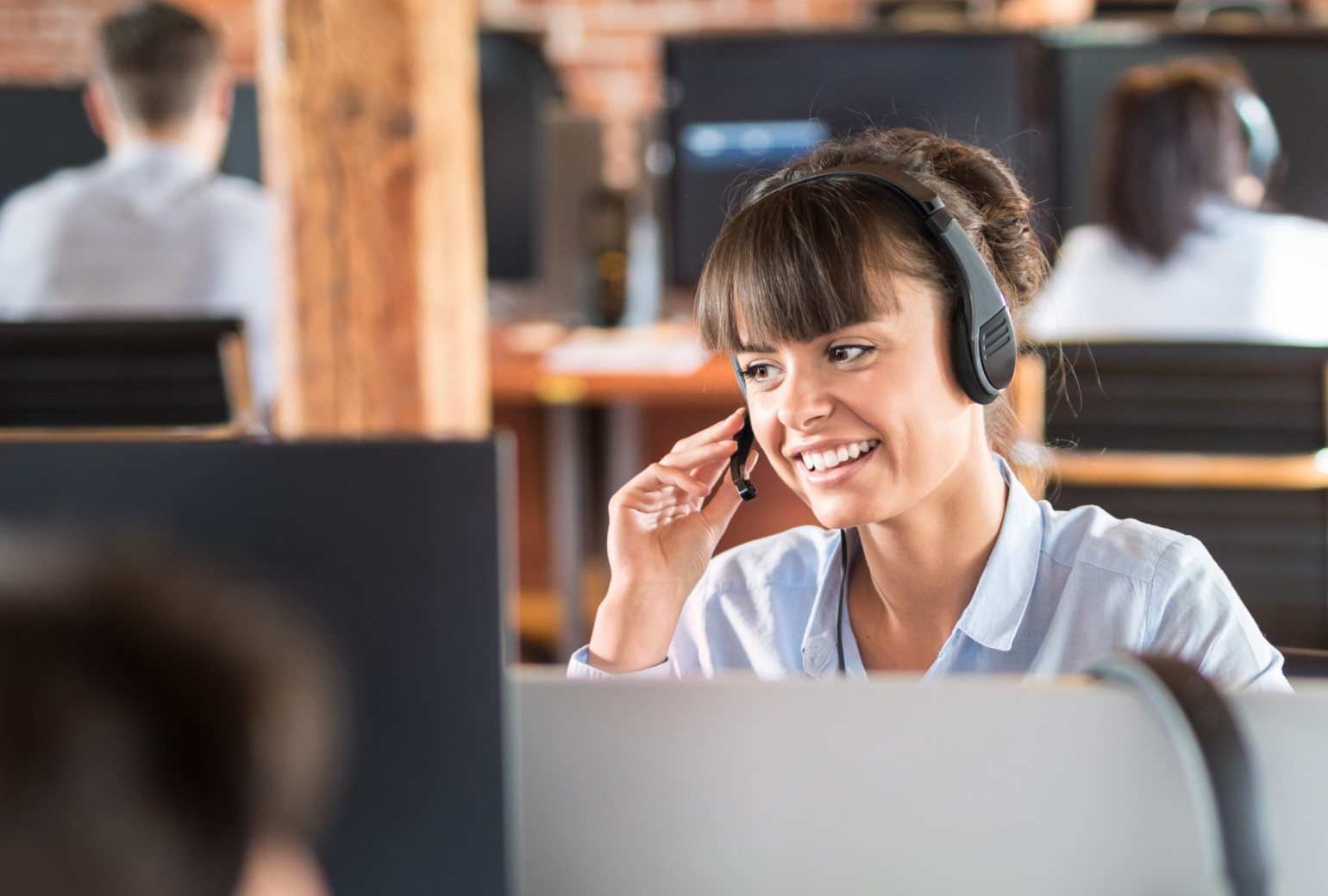Customer service rep smiling into a phone headset in a call center