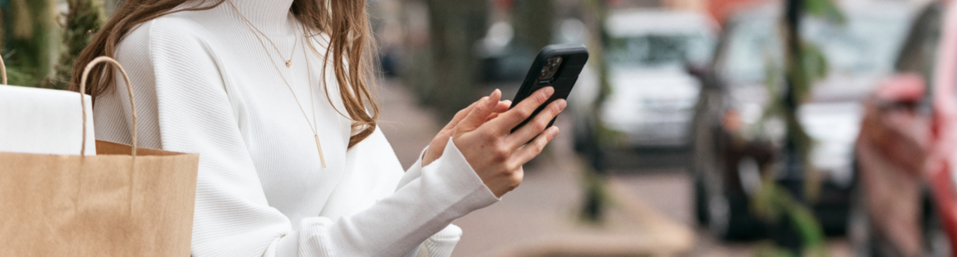 Seated woman holding a cellphone next to a shopping bag