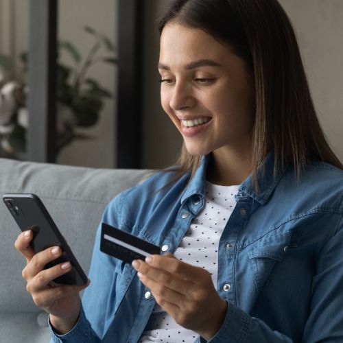 Smiling customer using credit card to purchase something on phone