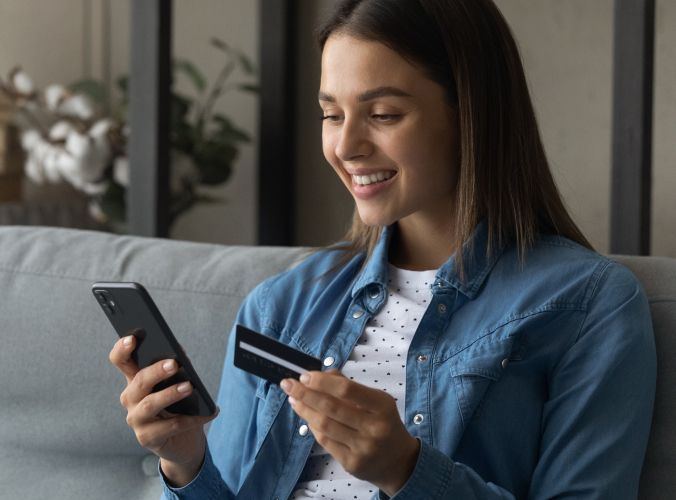 Smiling customer using credit card to purchase something on phone
