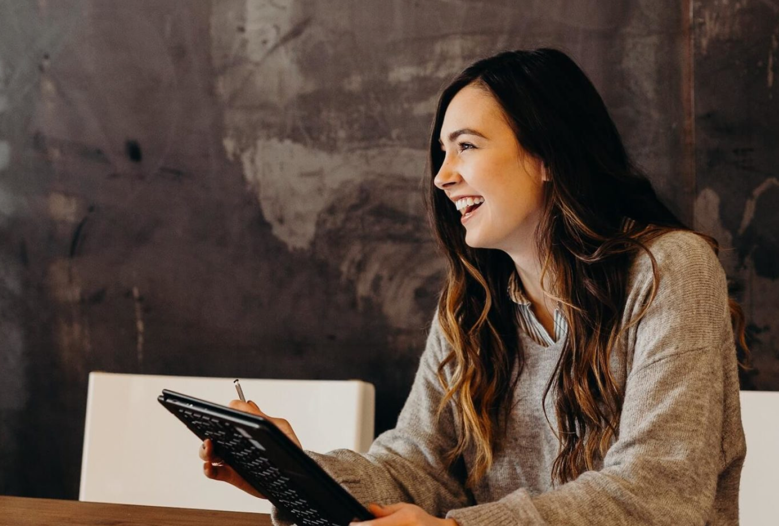 Image of a woman smiling and holding a tablet