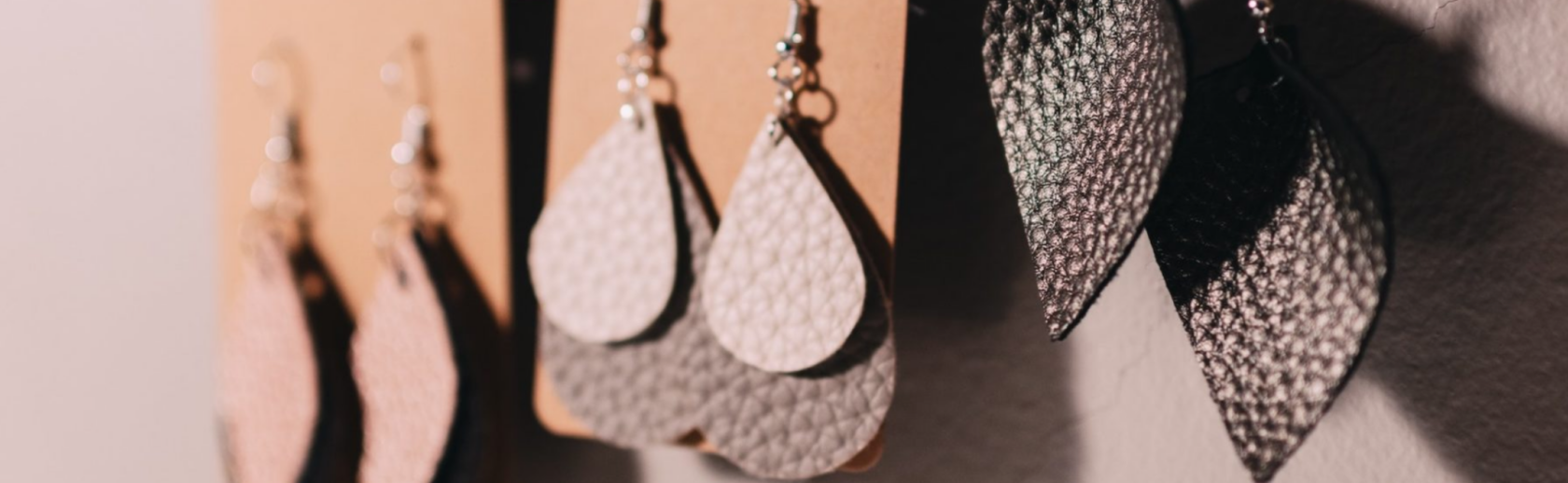 Three pairs of earrings hanging on a cork board