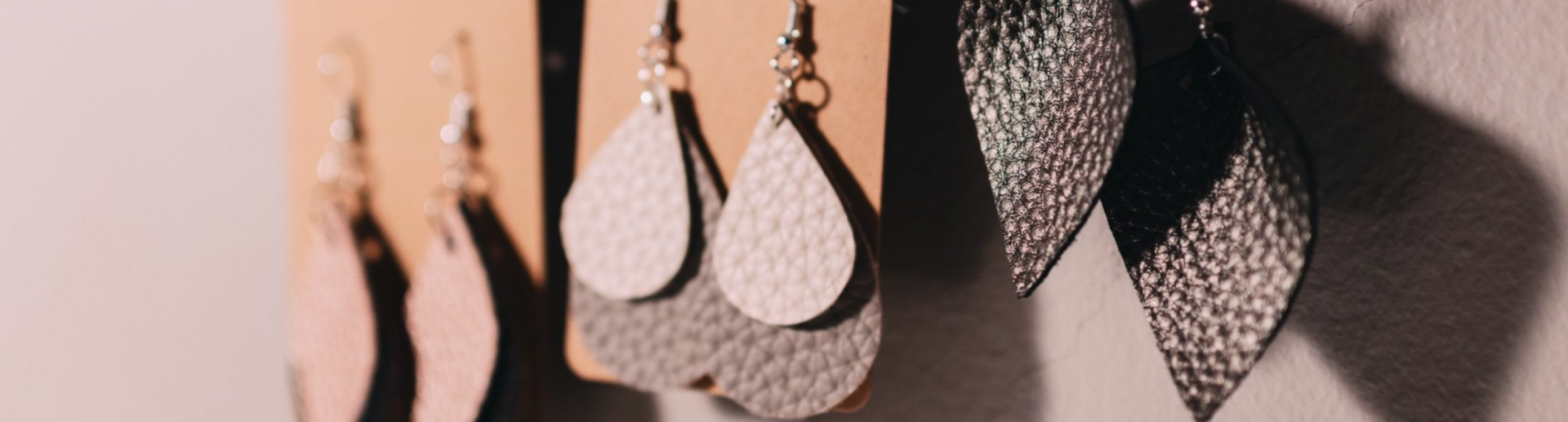 Three pairs of earrings hanging on a cork board
