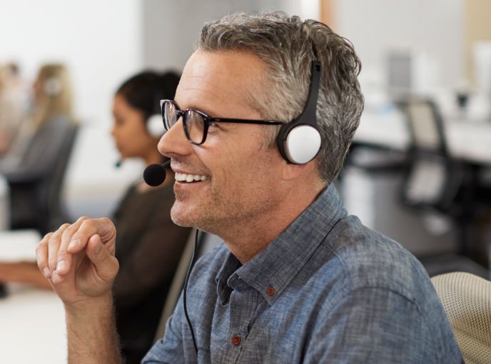 Man with a headset smiling at his computer