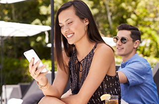 Smiling woman seated outdoors looking at her smartphone