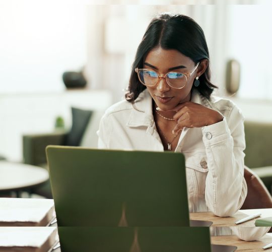 A man in a dark suit smiles confidently, standing with arms crossed against a light green background with subtle circular patterns.