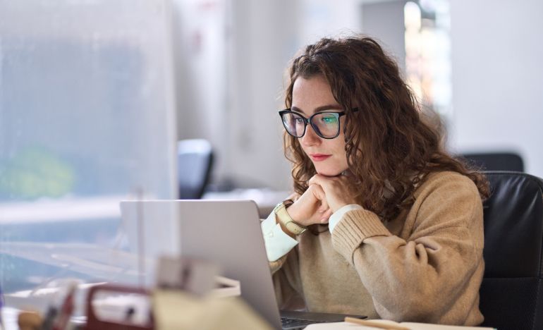 A CX leader looking at her laptop to learn ai terms for customer service
