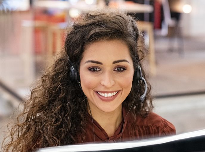 Woman with a headset smiling at her computer