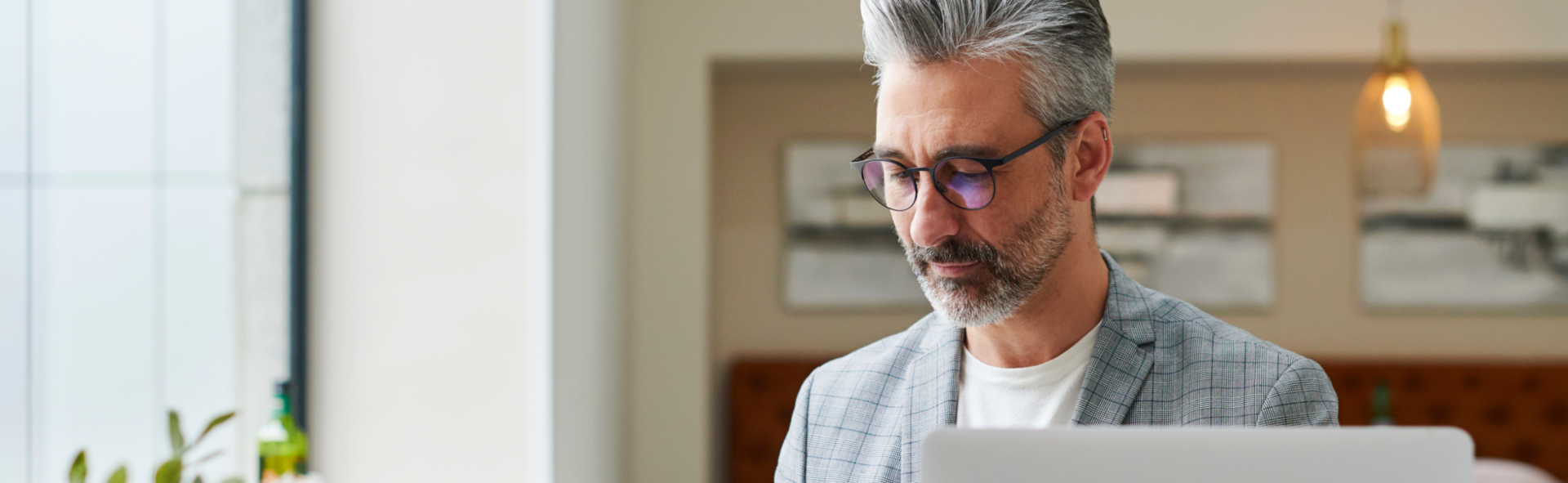 Bespectacled business man looking at his smartphone in front of a laptop
