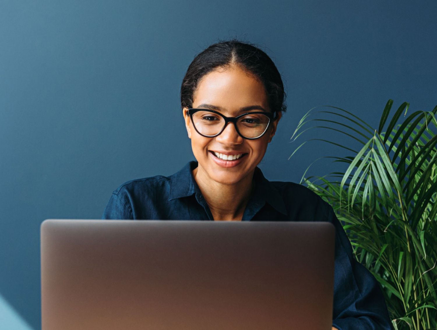Woman with glasses smiling at laptop