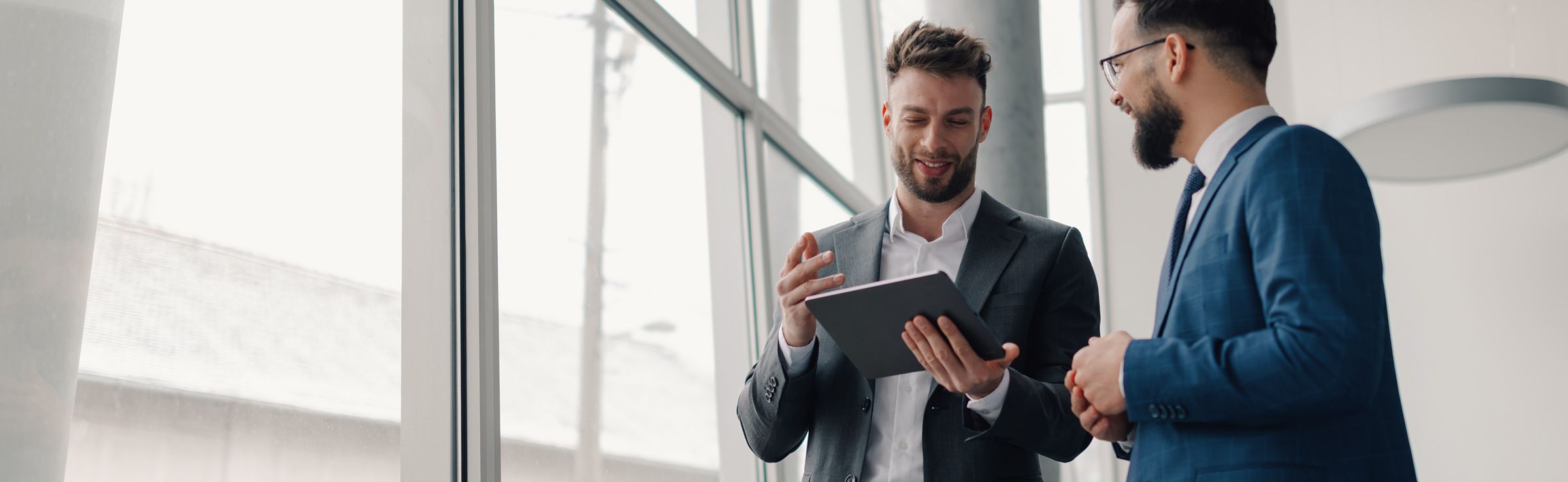 Two men talking while looking at a tablet