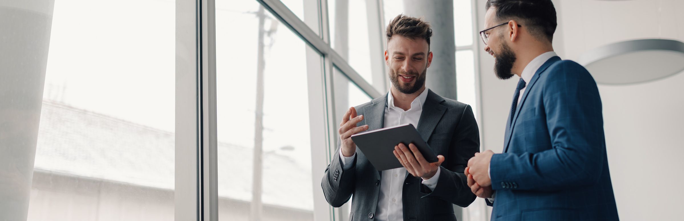 Two men talking while looking at a tablet
