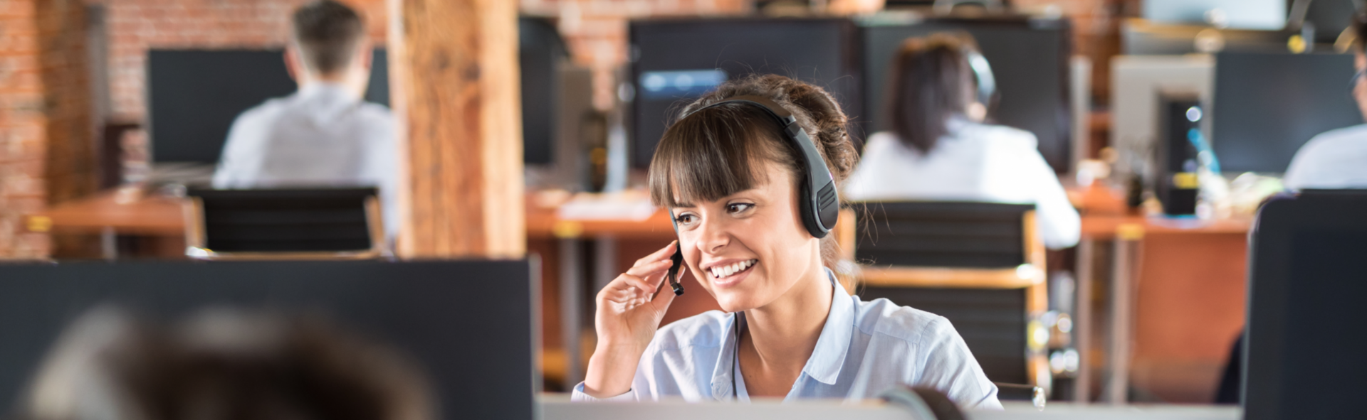 Customer service rep smiling into a phone headset in a call center