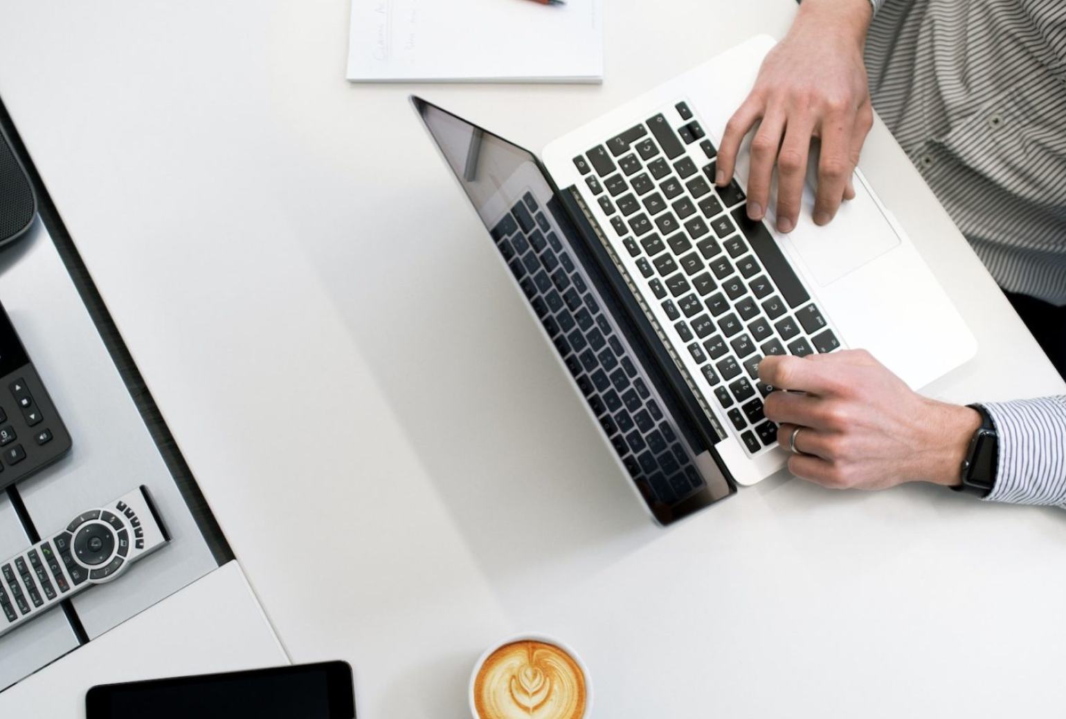 Image of a person sitting at a white desk typing on a laptop