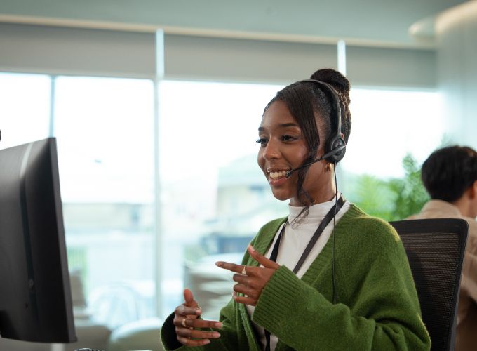 Customer support agent having a conversation on her headset and desktop computer