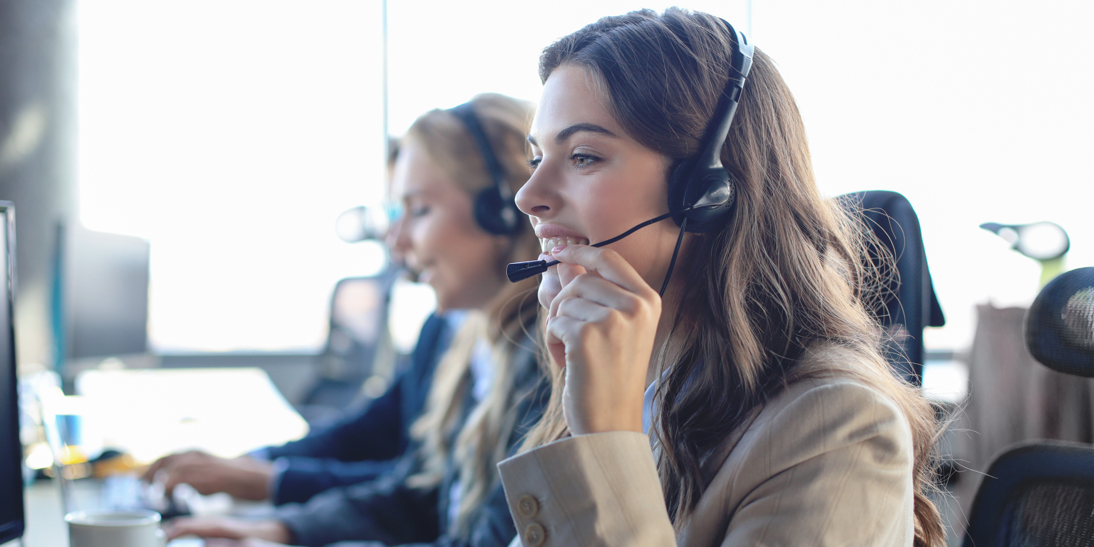 A person wearing a headset looks at a computer screen displaying financial data, including a colorful pie chart. The setting is professional and focused.