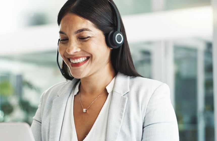Customer service agent wearing headset smiling at computer