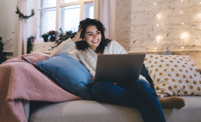 Smiling woman sitting on a couch with a laptop