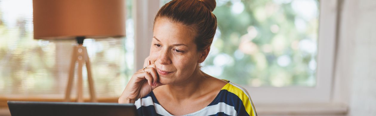 woman looking thoughtfully at laptop