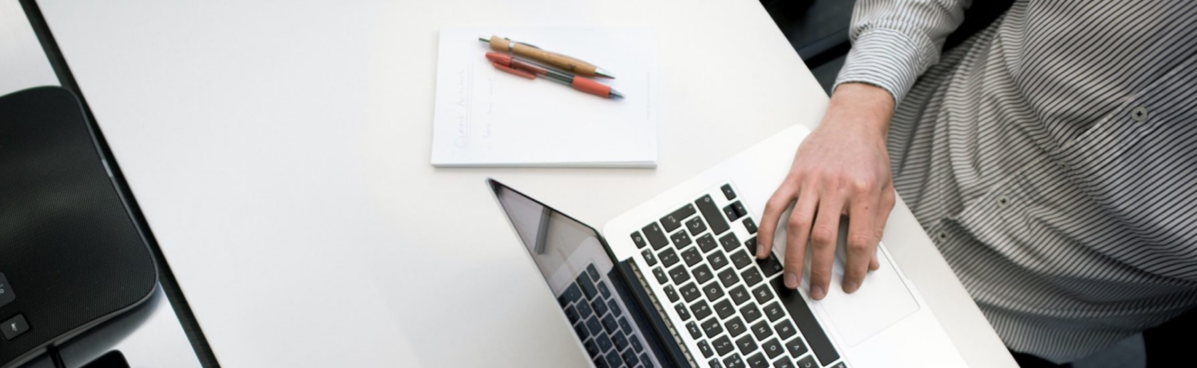 Image of a person sitting at a white desk typing on a laptop